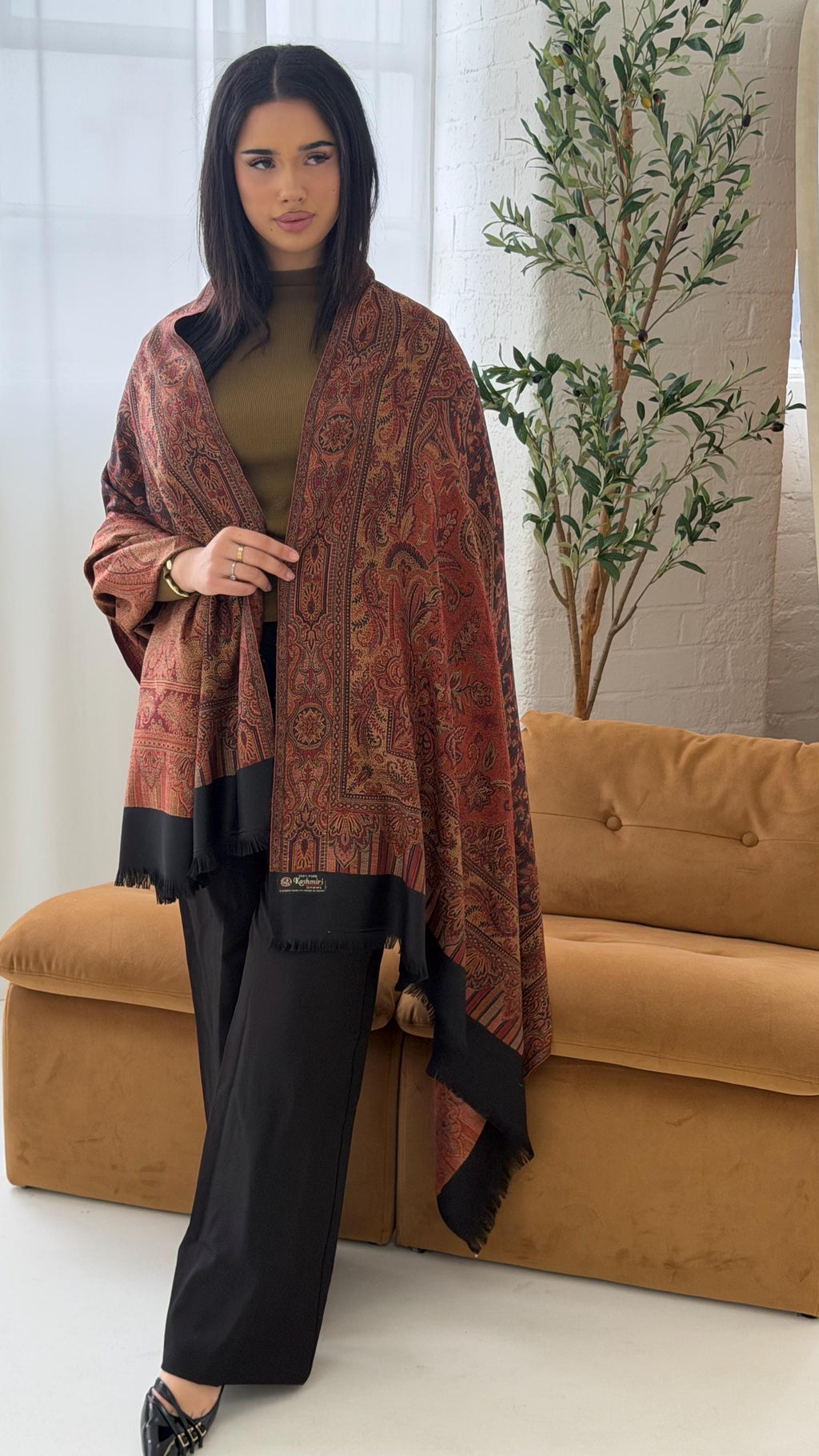 Woman wearing a black pashmina patterned shawl in a living room setting