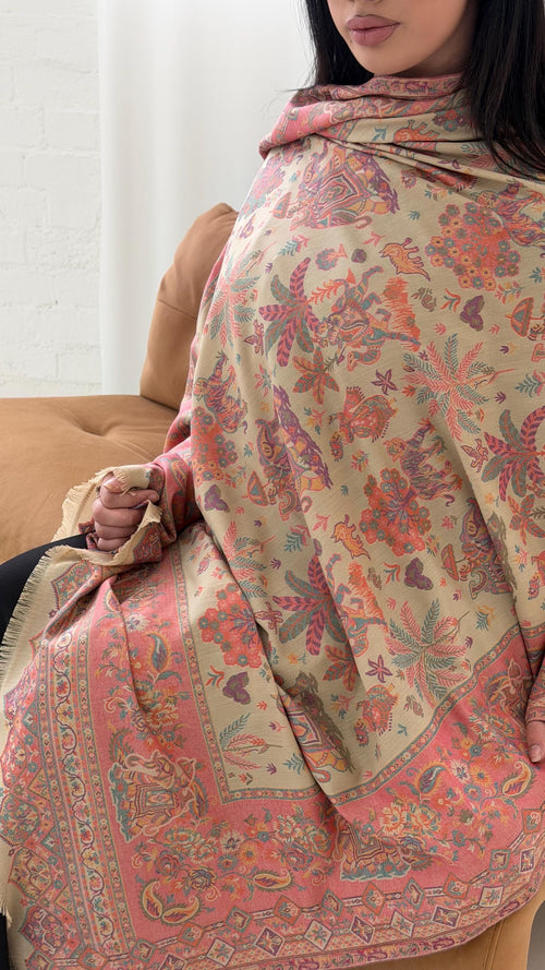 Woman wearing a beige patterned pashmina shawl with a neutral background