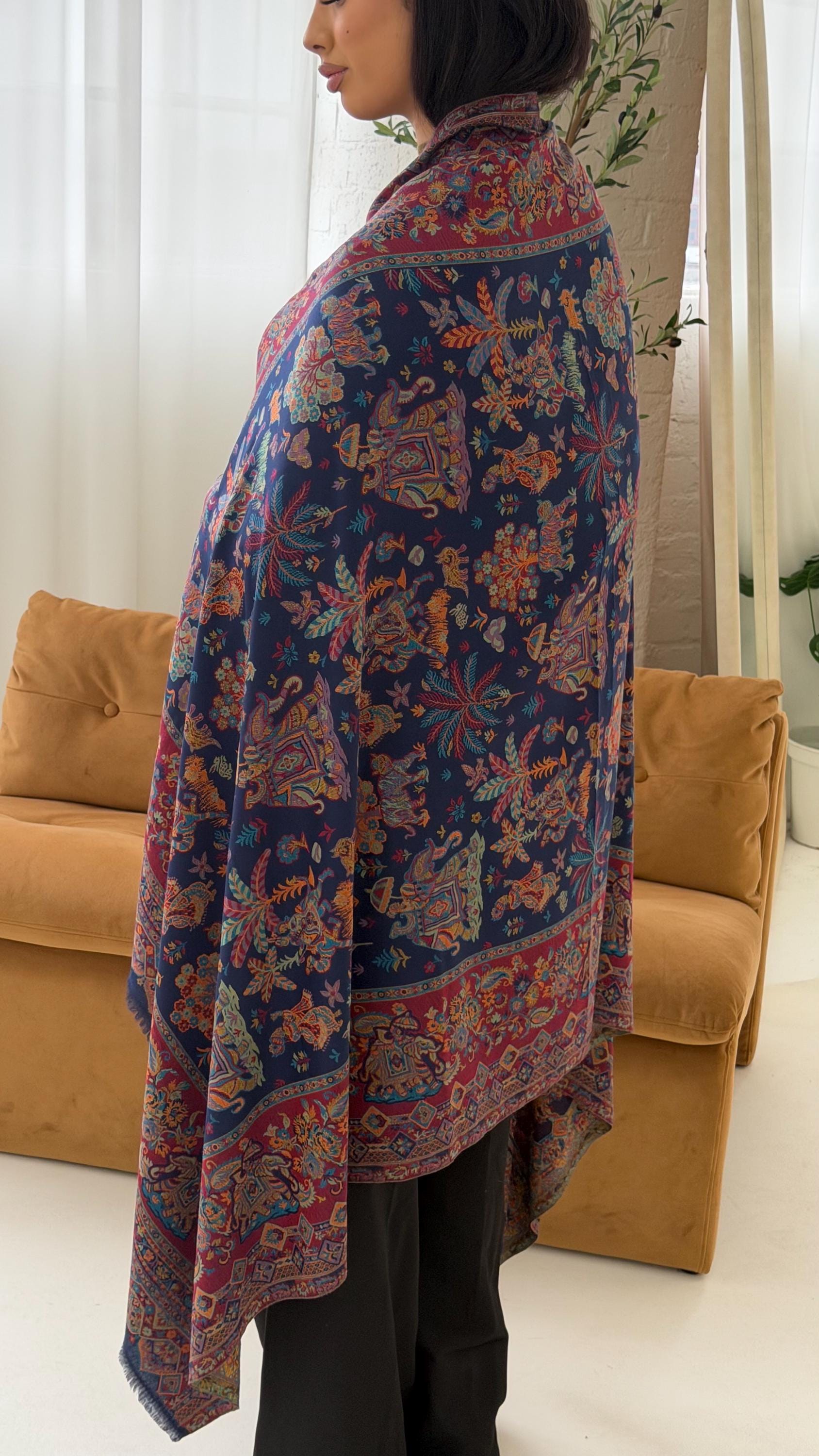 Person wearing a blue patterned pashmina shawl scarf  in a room with a couch and plant