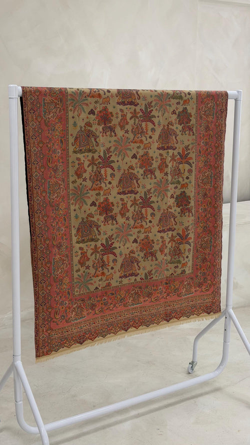 beige patterned pashmina shawl with intricate patterns on a white stand against a plain background