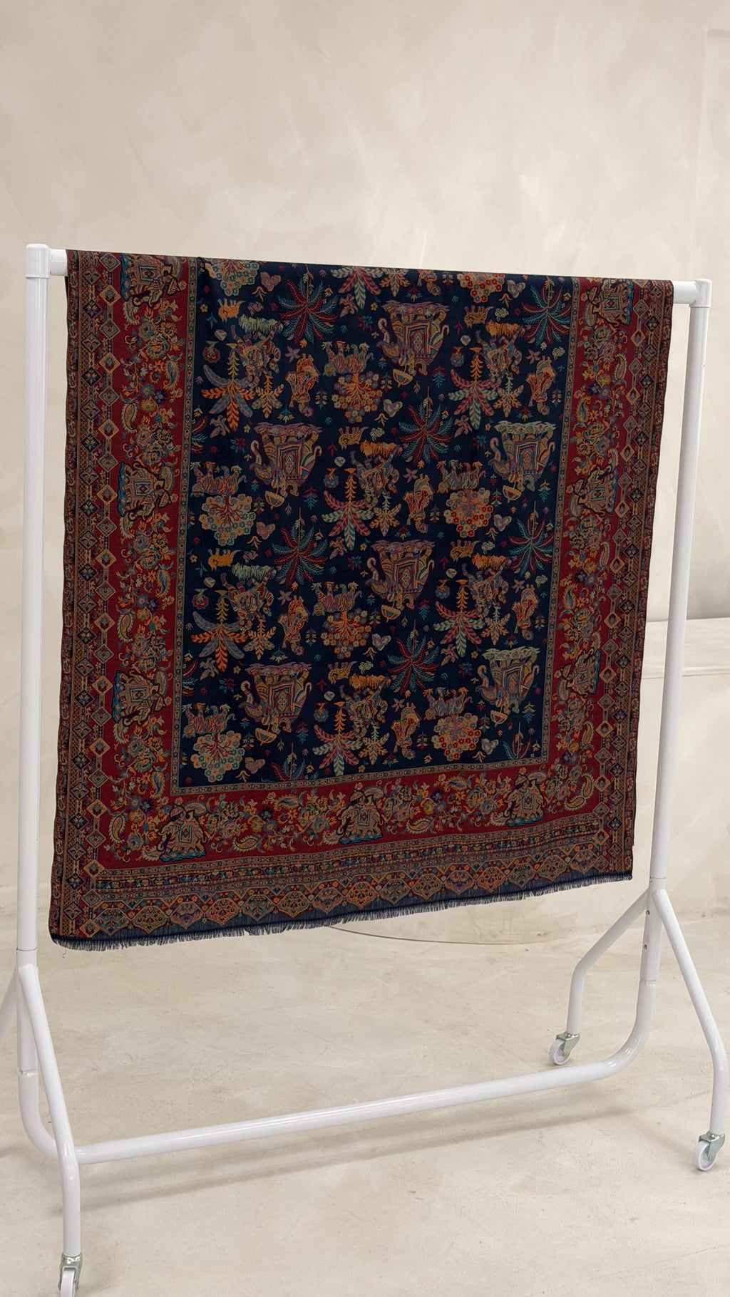 blue patterned pashmina shawl scarf  on a stand against a plain wall